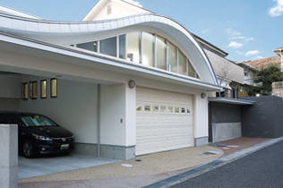 真っ白な外観とアーチ状のシルバーの屋根が印象的なガレージハウス。